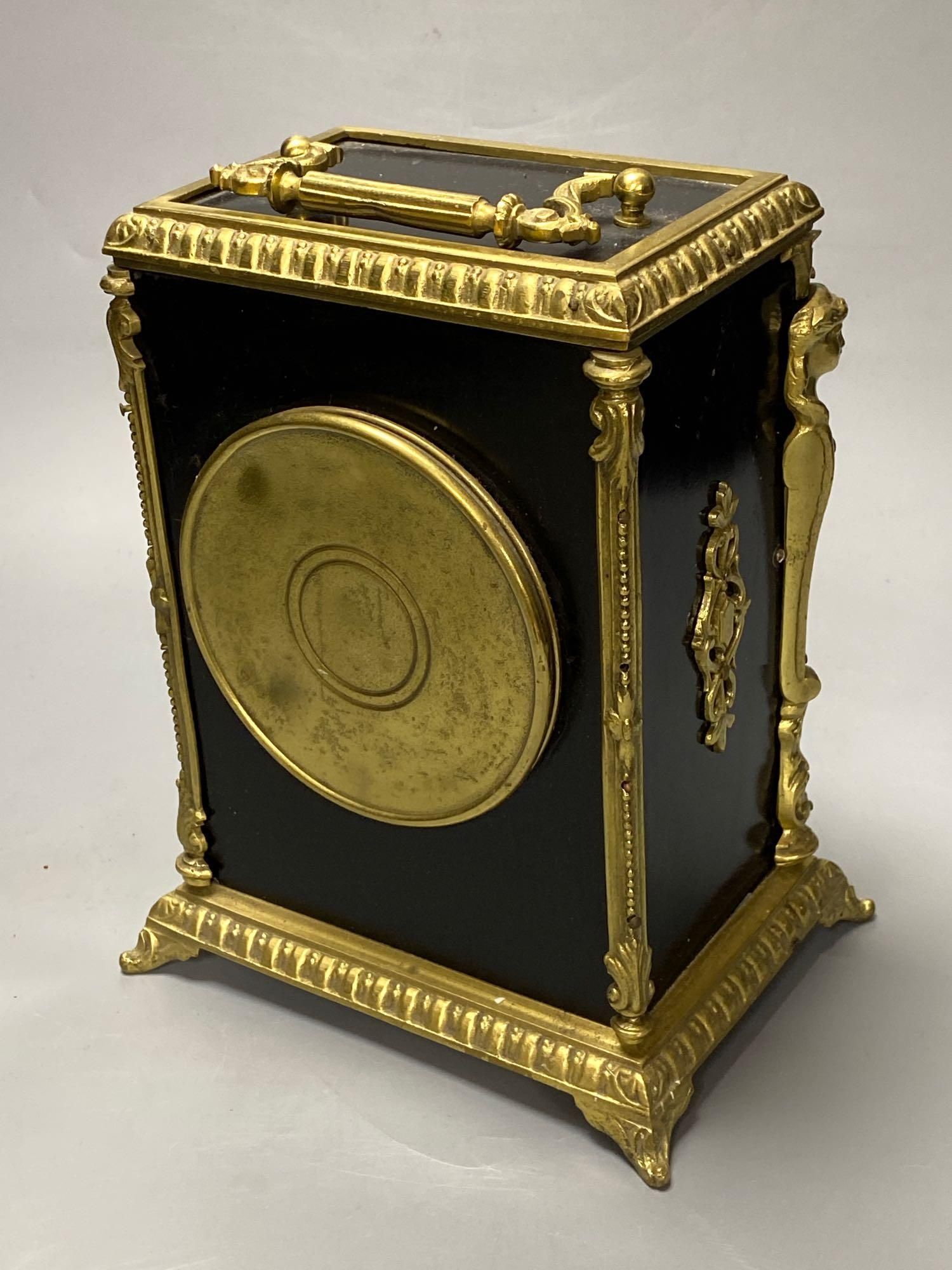 A French ebonised mantel clock with cast brass mounts, 9cm convex enamel dial, bell striking movement, height 27cm incl. handle